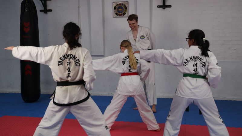 Three students performing the pattern Do-San in front of an instructor.